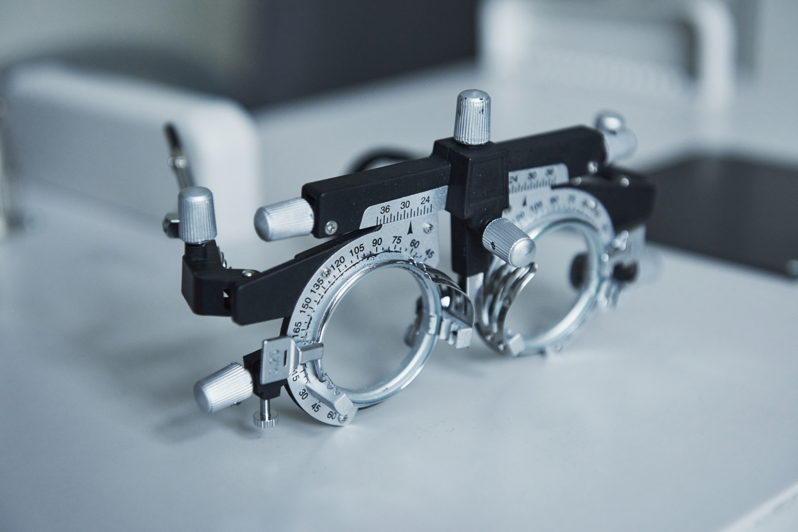 Photo from the side. Focused detailed close up photo of phoropter standing on the white table.